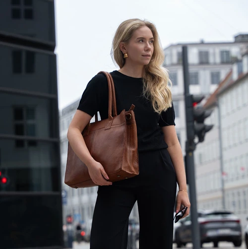 Ung kvinde med taske med plads til computer og bøger. Shop computertasker til studiet på neye.dk